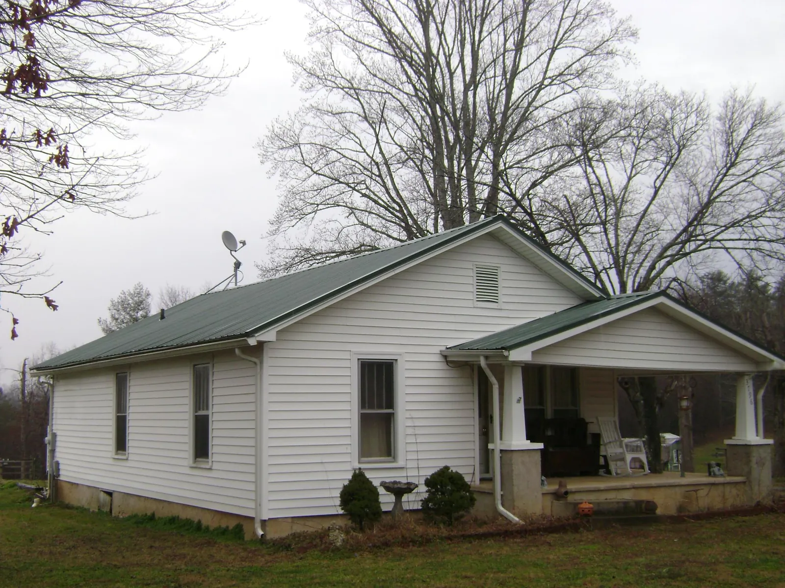 Green metal roof on a white bungalow with a side porch in Mansfield