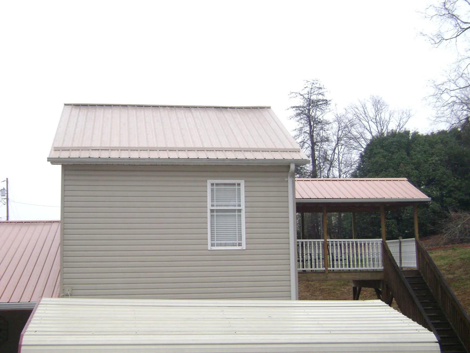 Tan metal roofs on a two story addition and attached porch, from a Roof Replacement job in Mansfield